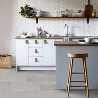 Modern kitchen with white cabinets, wooden bar stool, and gray floor tiles.